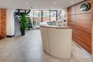 Land Rover office fit out by Westcountry Group, showing a wood cladded wall and desk in a reception area.