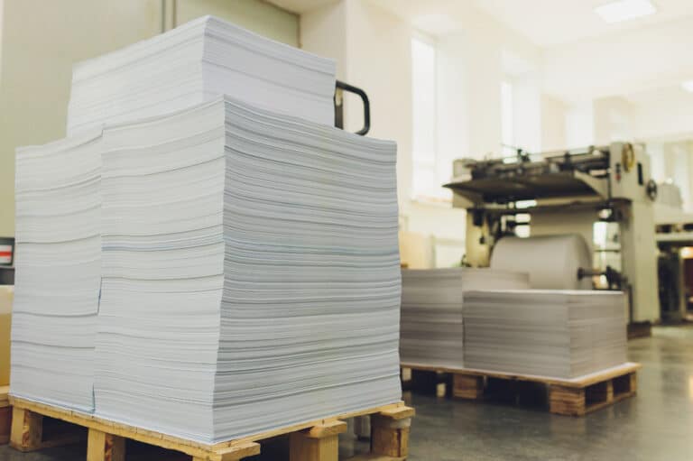 stacks of printed sheets of paper on wooden pallets.