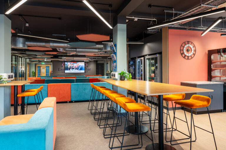 A vibrant and contemporary sixth form common area for Exeter School, featuring modern seating, high tables and bold colours.